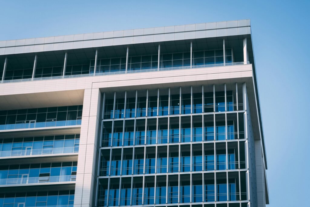 A modern high-rise office building with a distinctive glass facade under a clear blue sky.